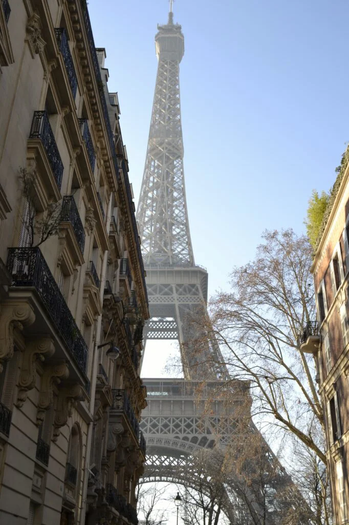 Curiosidades Torre Eiffel: historia, materiales y datos únicos Torre Eiffel enmarcada por arquitectura parisina en Rue de l