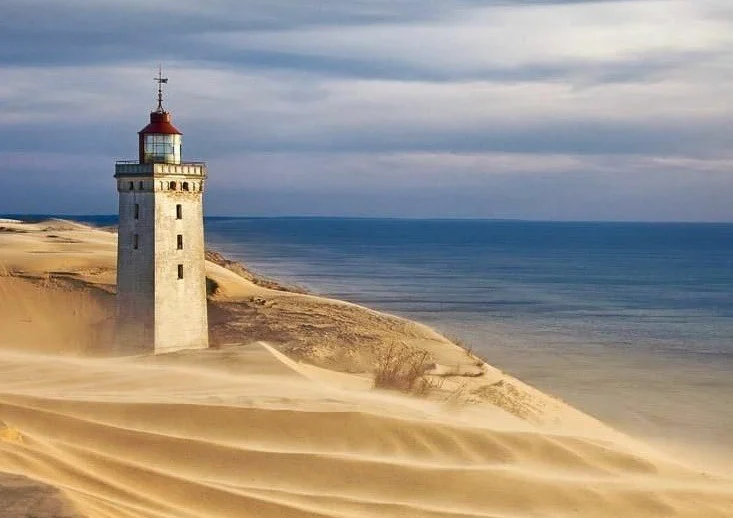 Faro de Rubjerg Knude unido a dunas costeras en Dinamarca