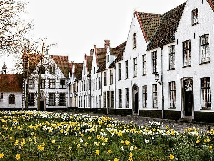 Qué Ver en Brujas: 15 Lugares Imprescindibles + Guía Casas blancas del Beguinaje de Brujas rodeando un patio ajardinado declarado Patrimonio UNESCO